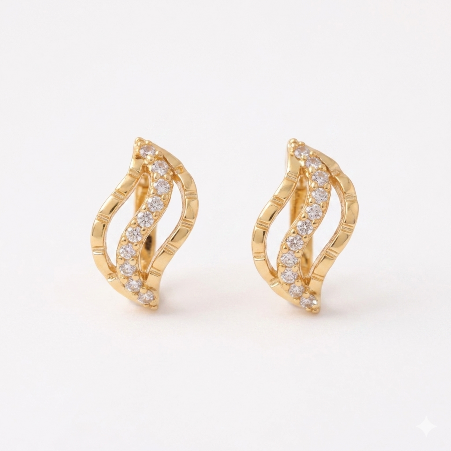A pair of gold-plated wave-shaped huggie hoop earrings for women featuring a curved row of clear crystals, shown on a clean white background.