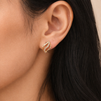 A gold-plated wave-shaped huggie hoop earrings for women featuring a curved row of clear crystals, shown on a model