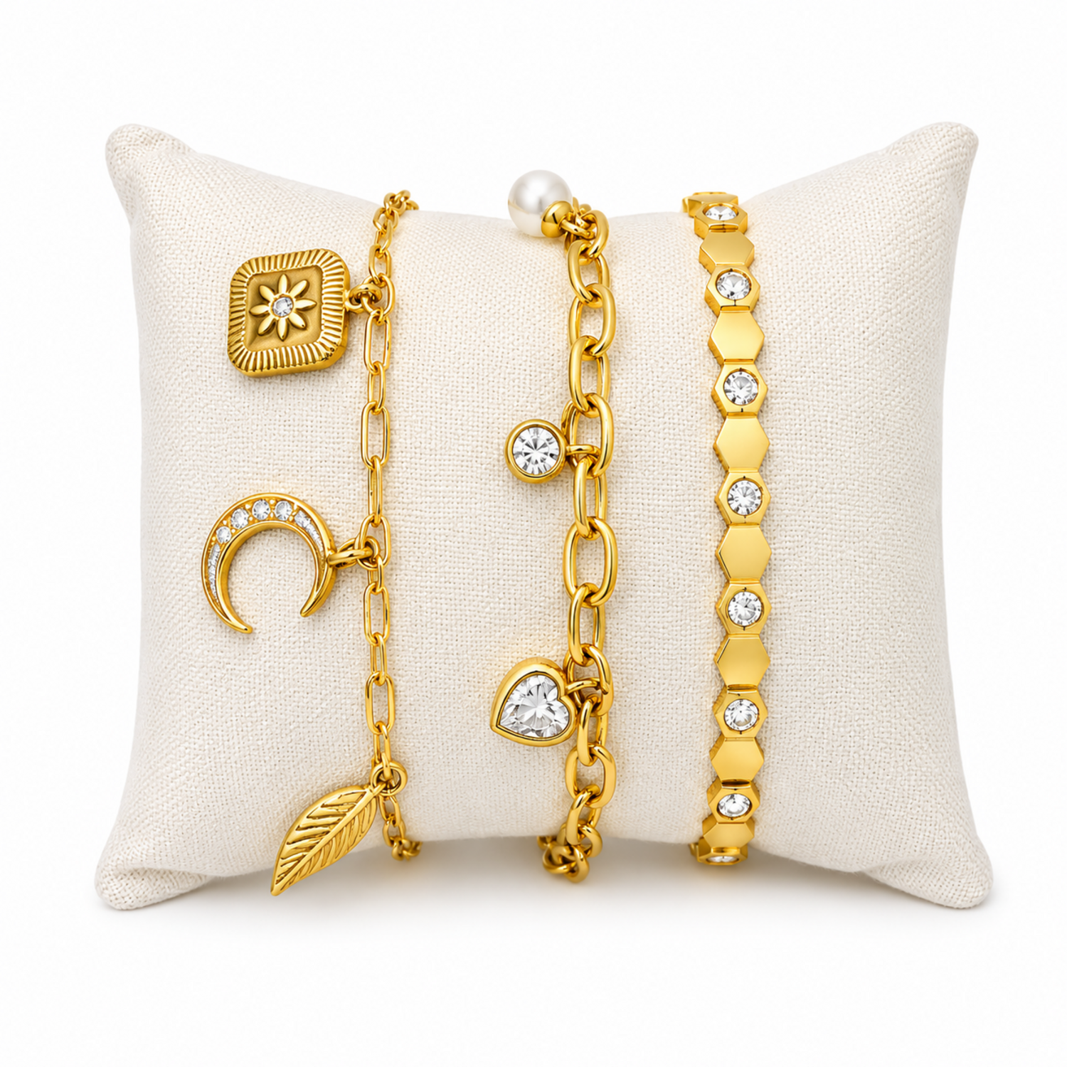 A three-piece gold-plated bracelet stack for women featuring a celestial charm link chain, a chunky paperclip charm chain with a pearl and heart drop, and a geometric honeycomb crystal bangle.