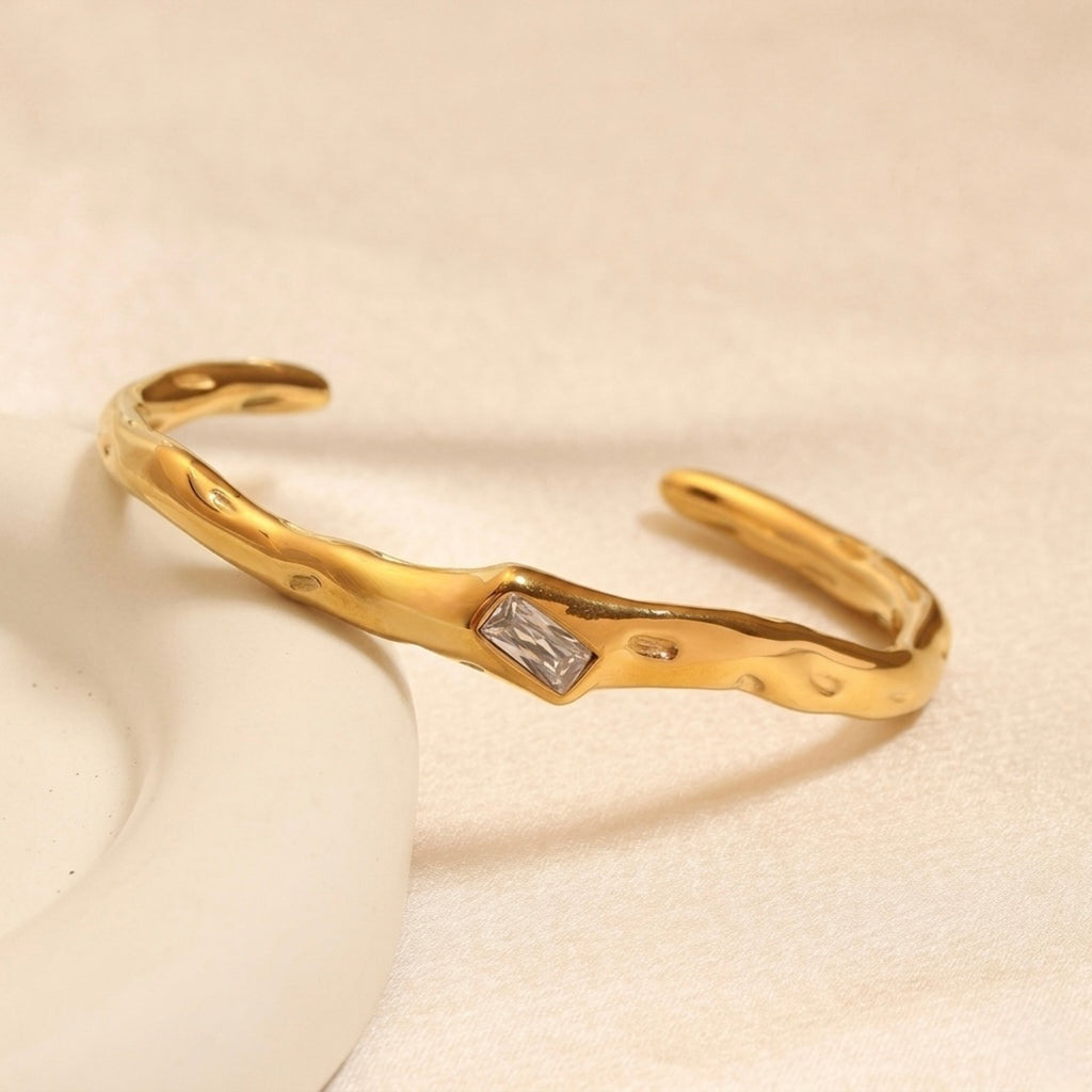 A gold-plated organic texture open-cuff bracelet for women featuring a central crystal solitaire.