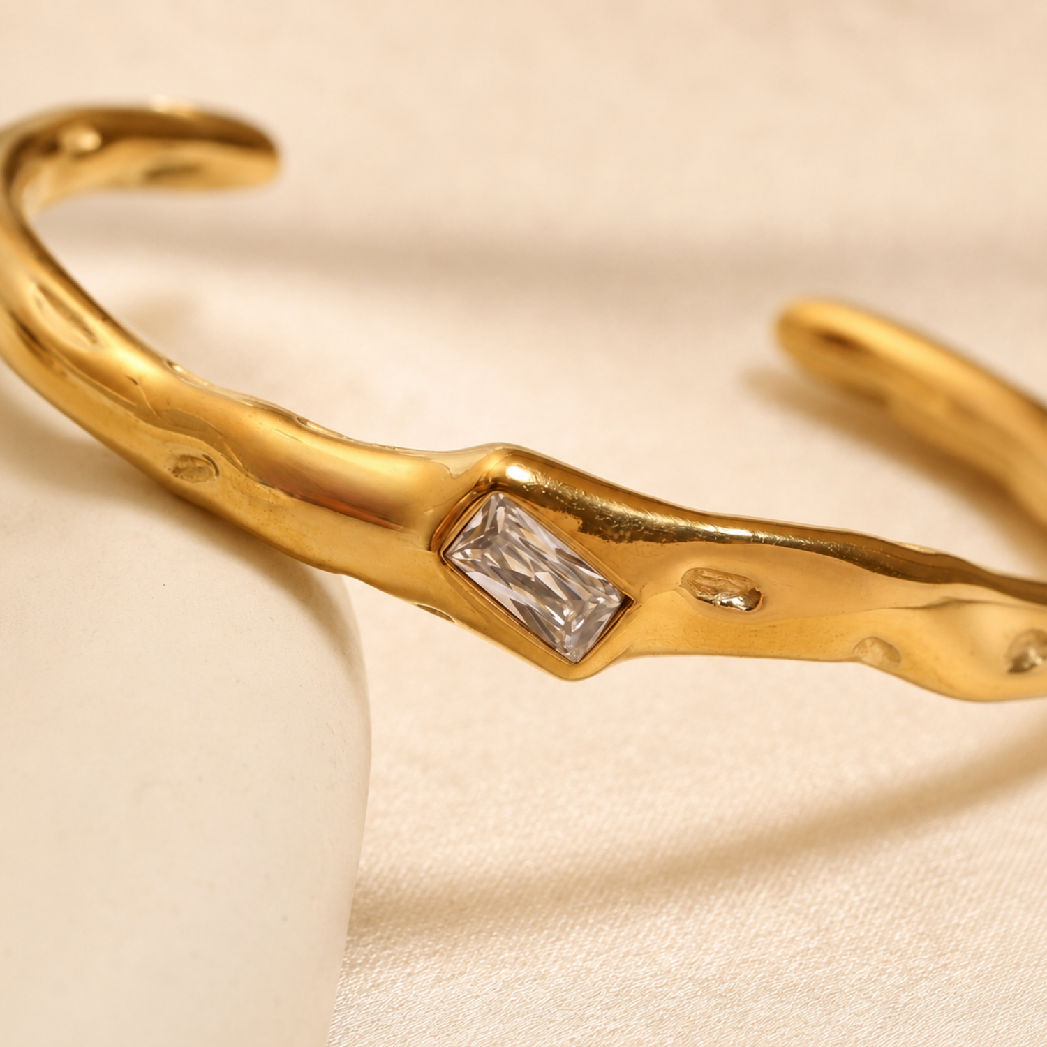 A close-view of a gold-plated organic texture open-cuff bracelet for women featuring a central crystal solitaire.