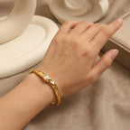 A gold-plated organic texture open-cuff bracelet for women featuring a central crystal solitaire, shown on a model