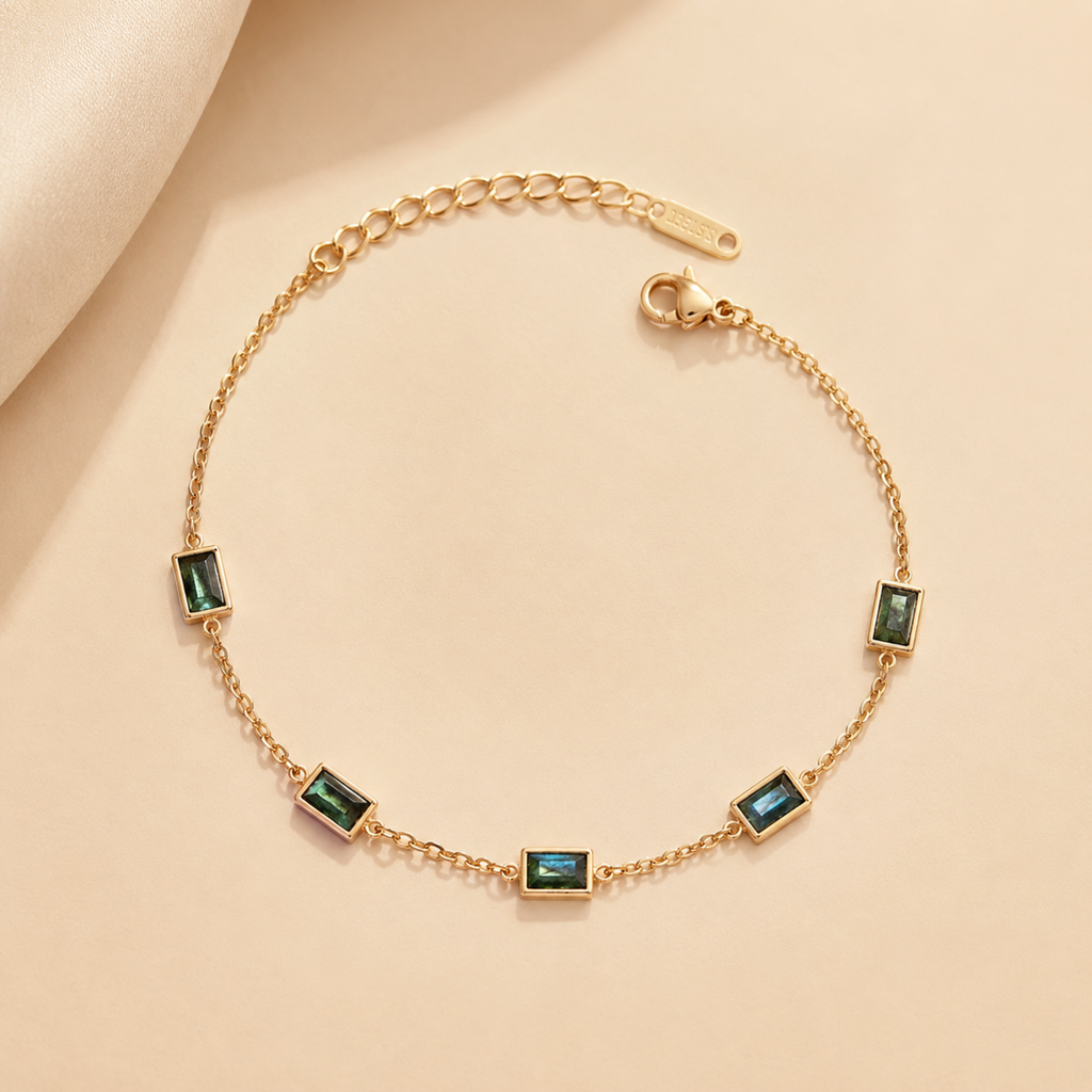 A gold-plated stainless steel chain bracelet for women featuring five rectangular emerald-green baguette stones.