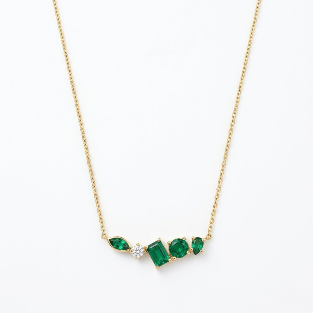 A gold-plated stainless steel chain for women featuring an asymmetrical pendant bar set with various emerald green and white crystal stones