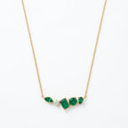 A gold-plated stainless steel chain for women featuring an asymmetrical pendant bar set with various emerald green and white crystal stones