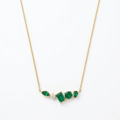 A gold-plated stainless steel chain for women featuring an asymmetrical pendant bar set with various emerald green and white crystal stones