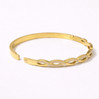 A side view of a high-quality gold-plated infinity braid bangle for women featuring pavé-set white stones on a white background