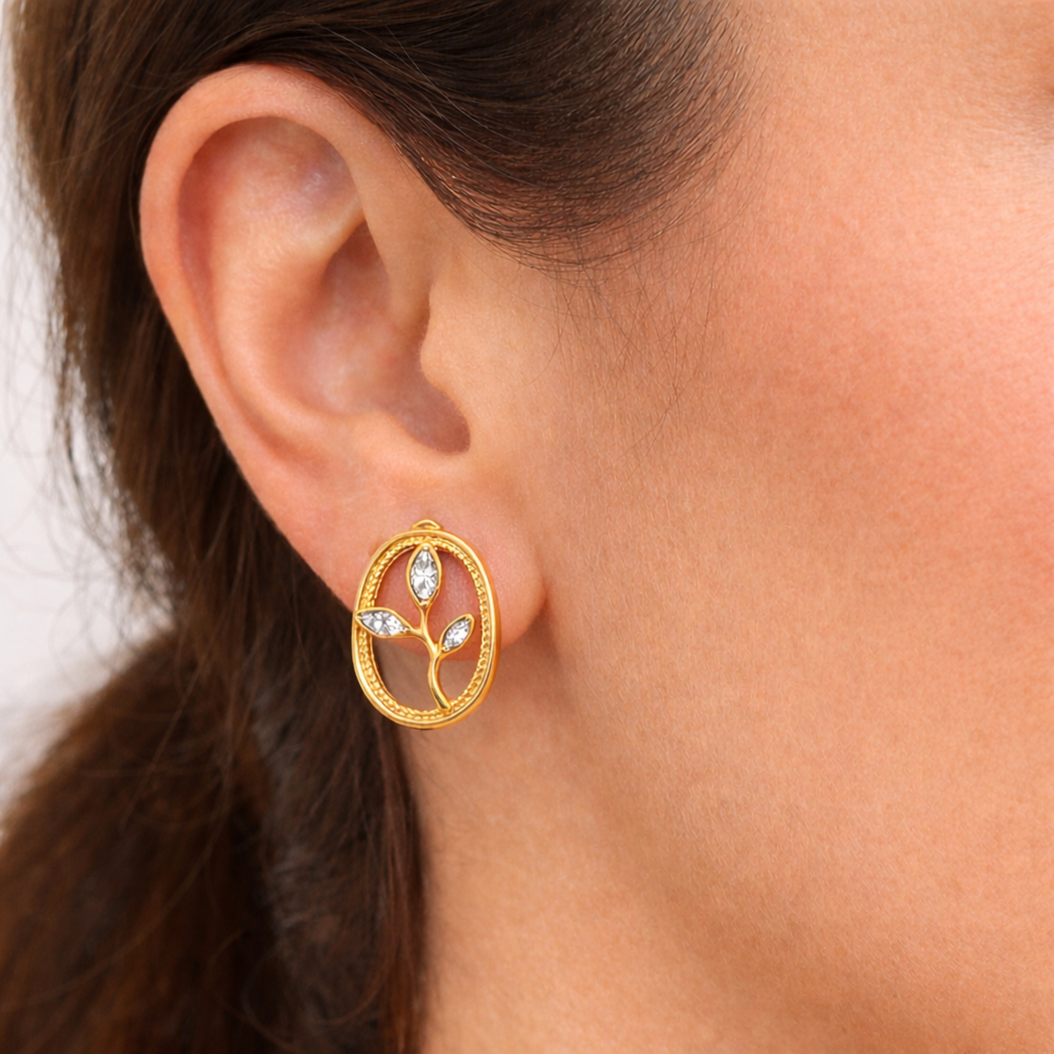 A gold-plated oval stud earrings for women featuring an branch design with three marquise crystal leaves, shown on a model
