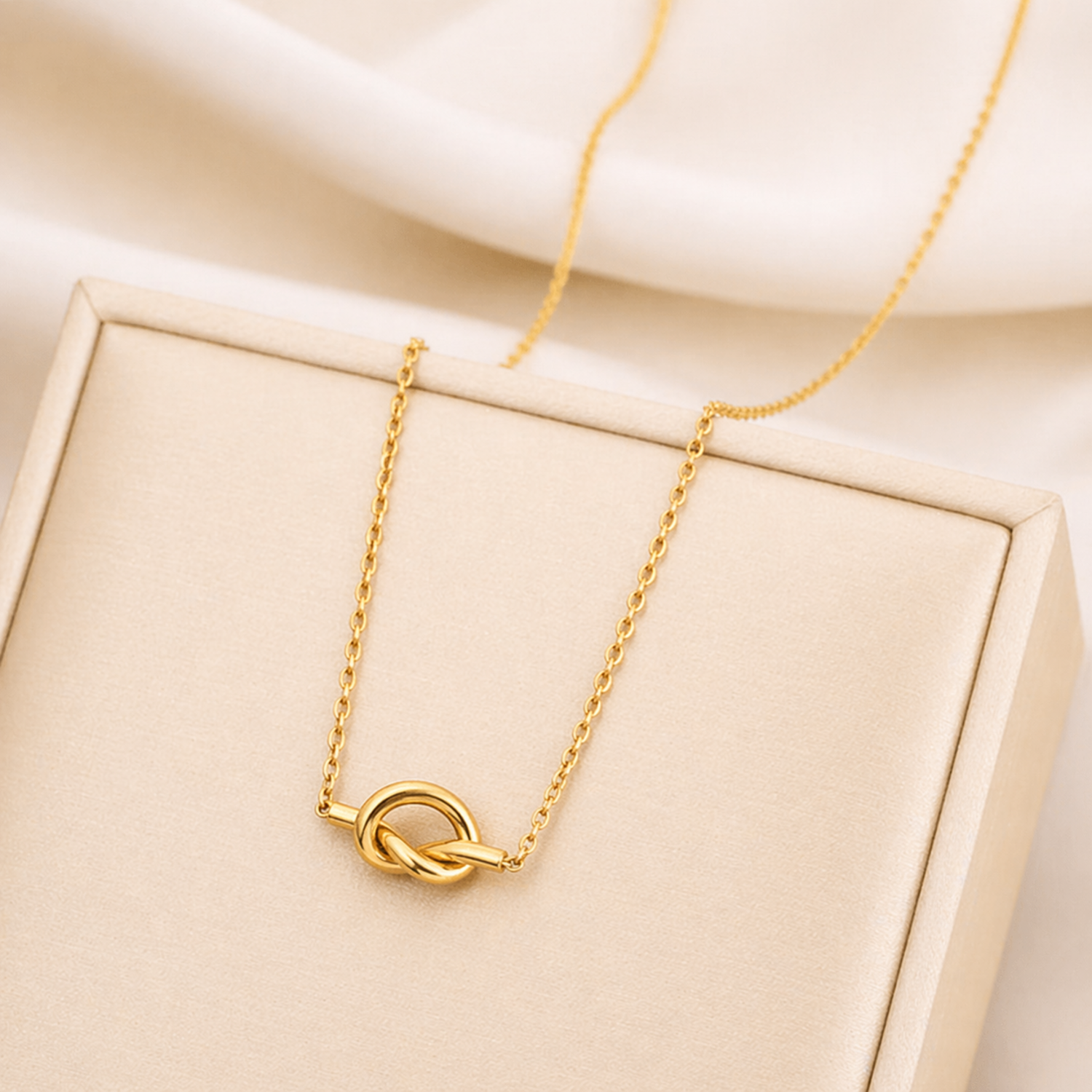 A gold-plated stainless steel chain for women featuring a polished, sculptural knot pendant on a delicate link chain