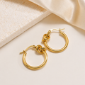 A pair of gold-plated hoop earrings for women featuring a central love-knot design, shown on a white surface
