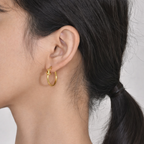 A gold-plated hoop earrings for women featuring a central love-knot design, shown on a model