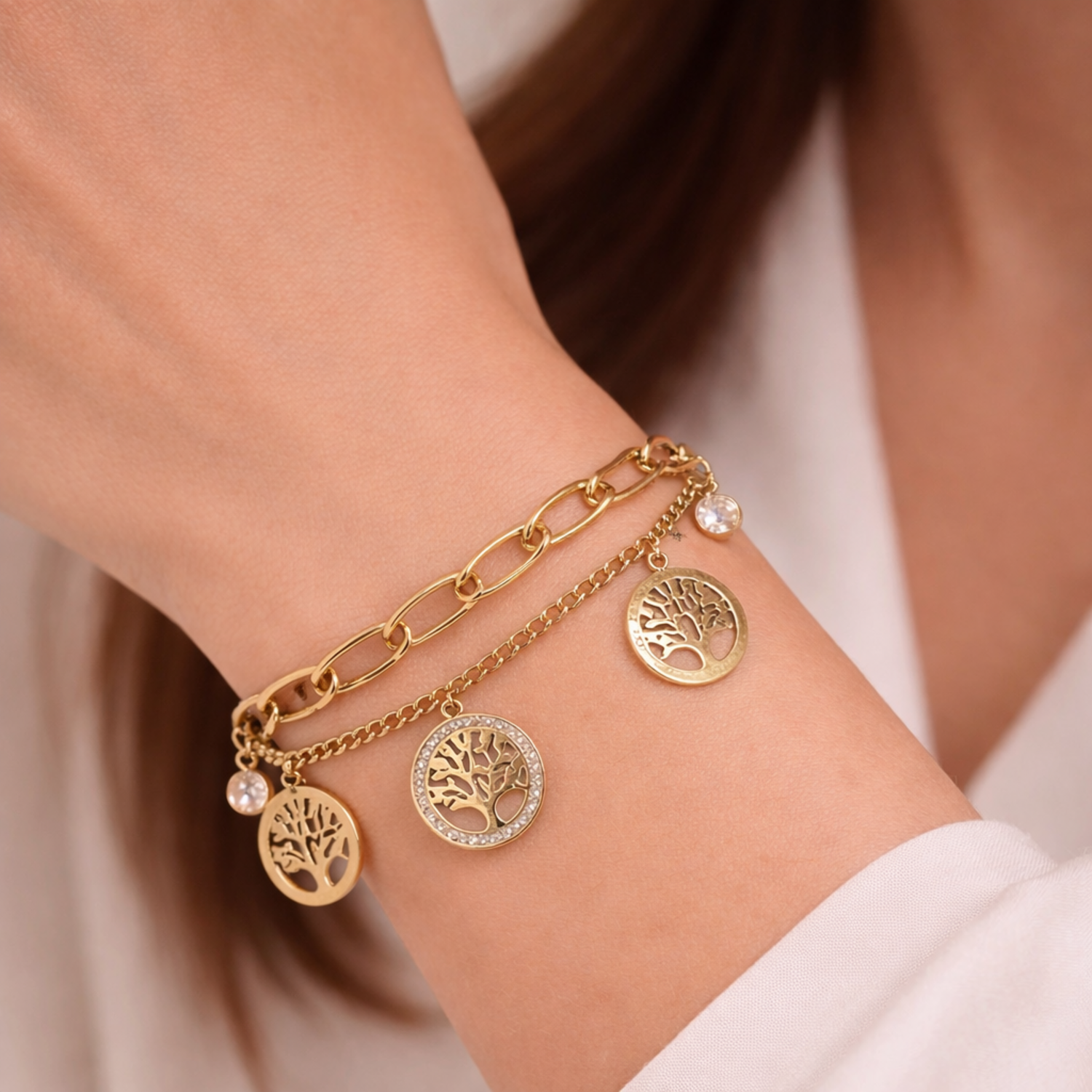 A dual-layer gold-plated chain bracelet for women featuring Tree of Life charms and clear crystal accents on a model hand