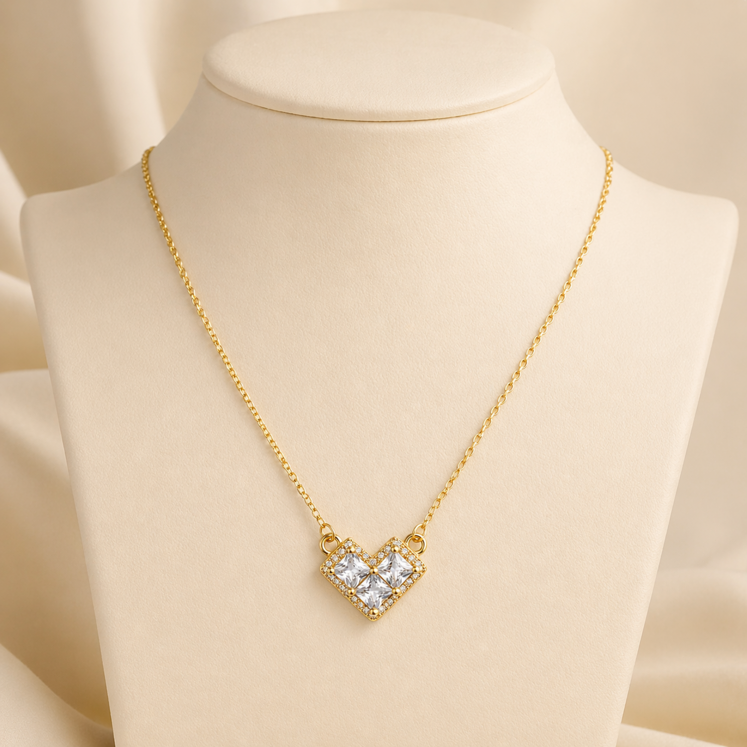 A close-view of a gold-plated stainless steel chain for women featuring a heart-shaped pendant set with three large square crystals and a sparkling pavé halo.