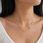 A gold-plated stainless steel chain for women featuring five crystal-accented feather station charms, shown on a model