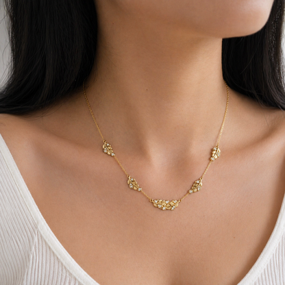 A gold-plated stainless steel chain for women featuring five crystal-accented feather station charms, shown on a model