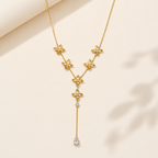 A gold-plated stainless steel chain for women in a Y-drop lariat style, featuring golden flowers and a pear-shaped crystal pendant