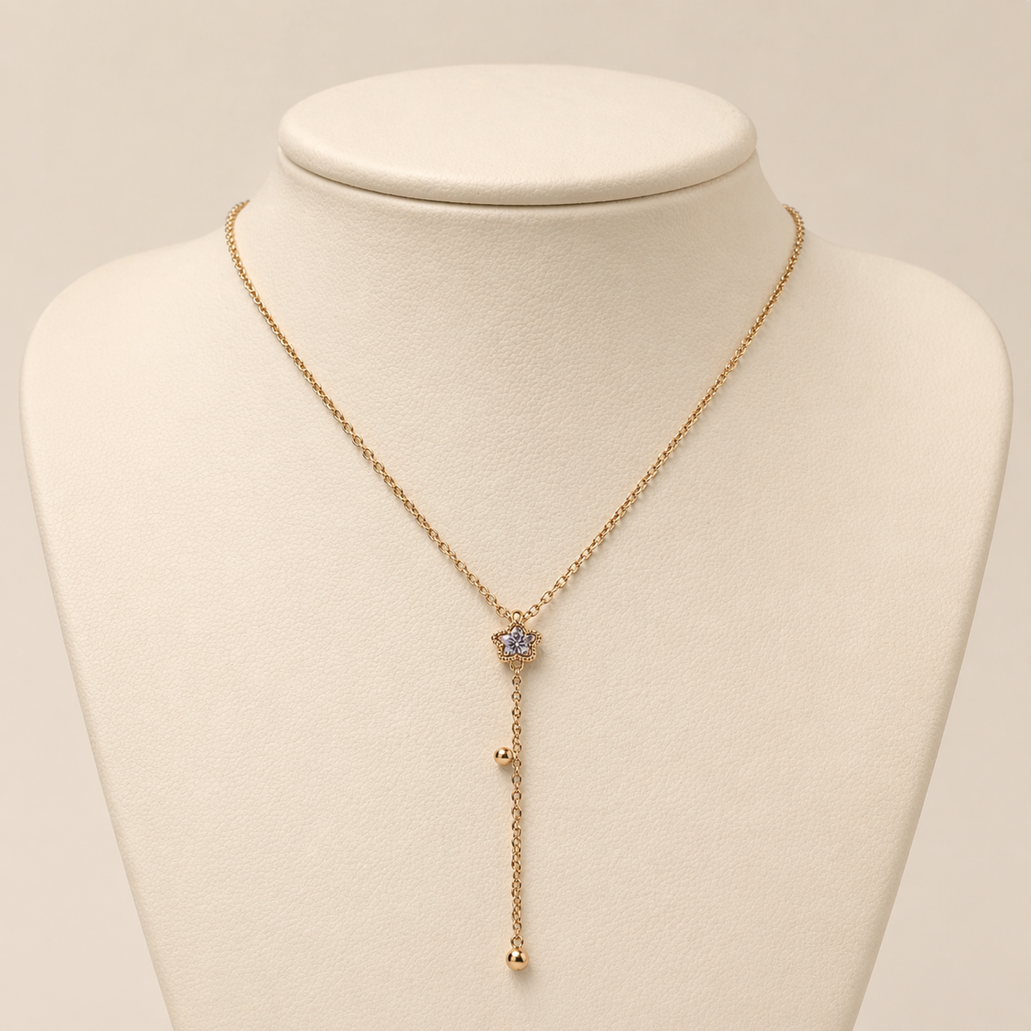 A gold-plated stainless steel Y-shaped necklace for women featuring a small crystal flower pendant and a dangling chain with gold beads