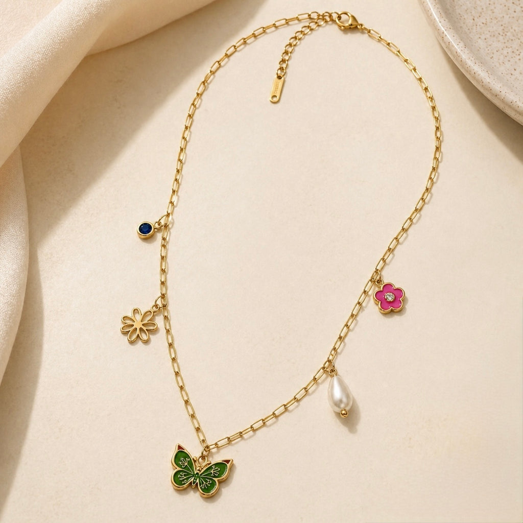 A gold-plated stainless steel chain for women featuring paperclip links and five nature-themed charms including a green butterfly, pink flower, and pearl.