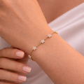 A delicate gold-plated chain bracelet for women featuring five star-shaped floral crystal stations, shown on a model hand