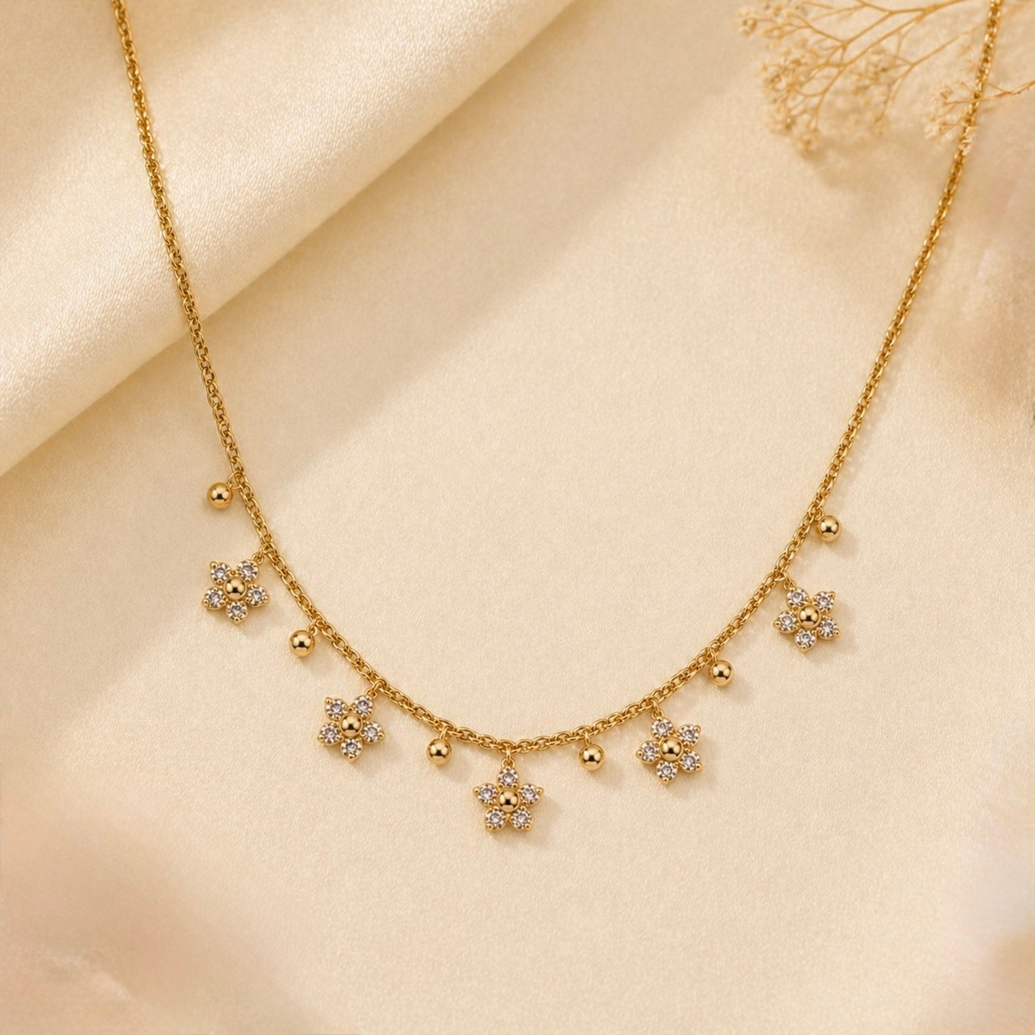 A gold-plated stainless steel chain for women featuring five crystal-encrusted flower charms and small gold beads