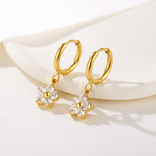 A pair of gold-plated hoop earrings for women featuring a dangling flower-shaped charm made of clear crystals