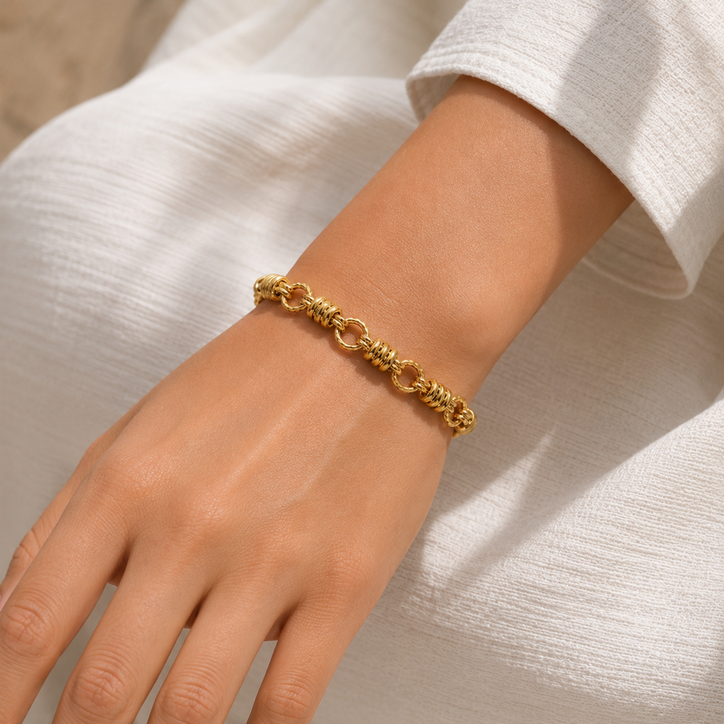 A gold-plated chain bracelet for women featuring thick polished links and textured coiled metal stations, shown on a model