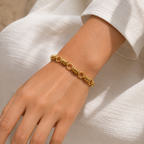 A gold-plated chain bracelet for women featuring thick polished links and textured coiled metal stations, shown on a model