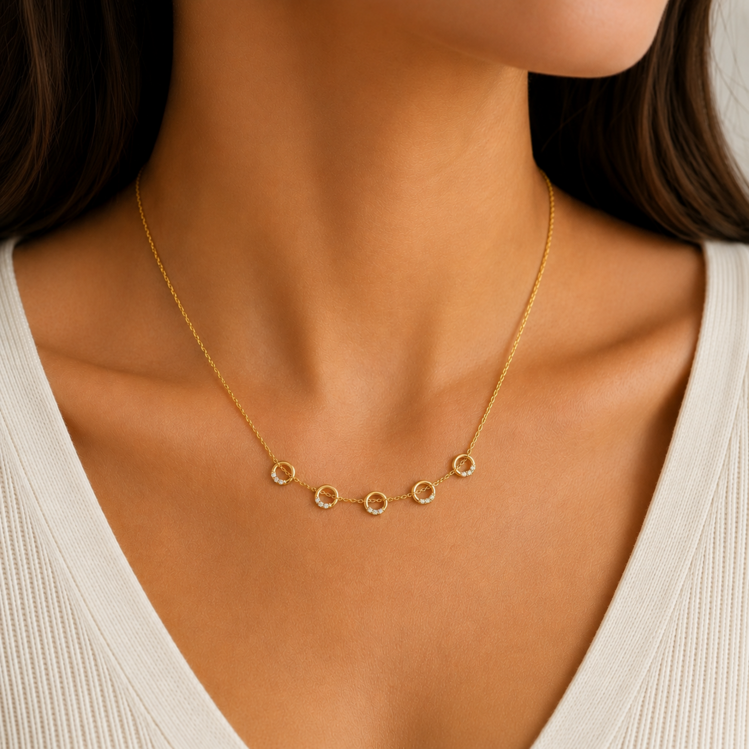 A gold-plated stainless steel chain for women featuring five circular station charms accented with crystals, shown on a model