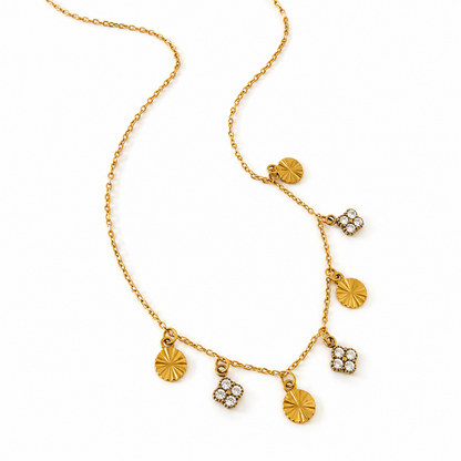 A gold chain necklace with multiple dangling charms, including textured round discs and floral clover-shaped pendants, photographed on a clean white background.