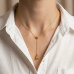 A gold-plated stainless steel chain for women featuring a Y-shaped lariat design with two polished teardrop-shaped pendants shown on a model