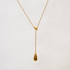 A gold-plated stainless steel chain for women featuring a Y-shaped lariat design with two polished teardrop-shaped pendants on a white textured background.