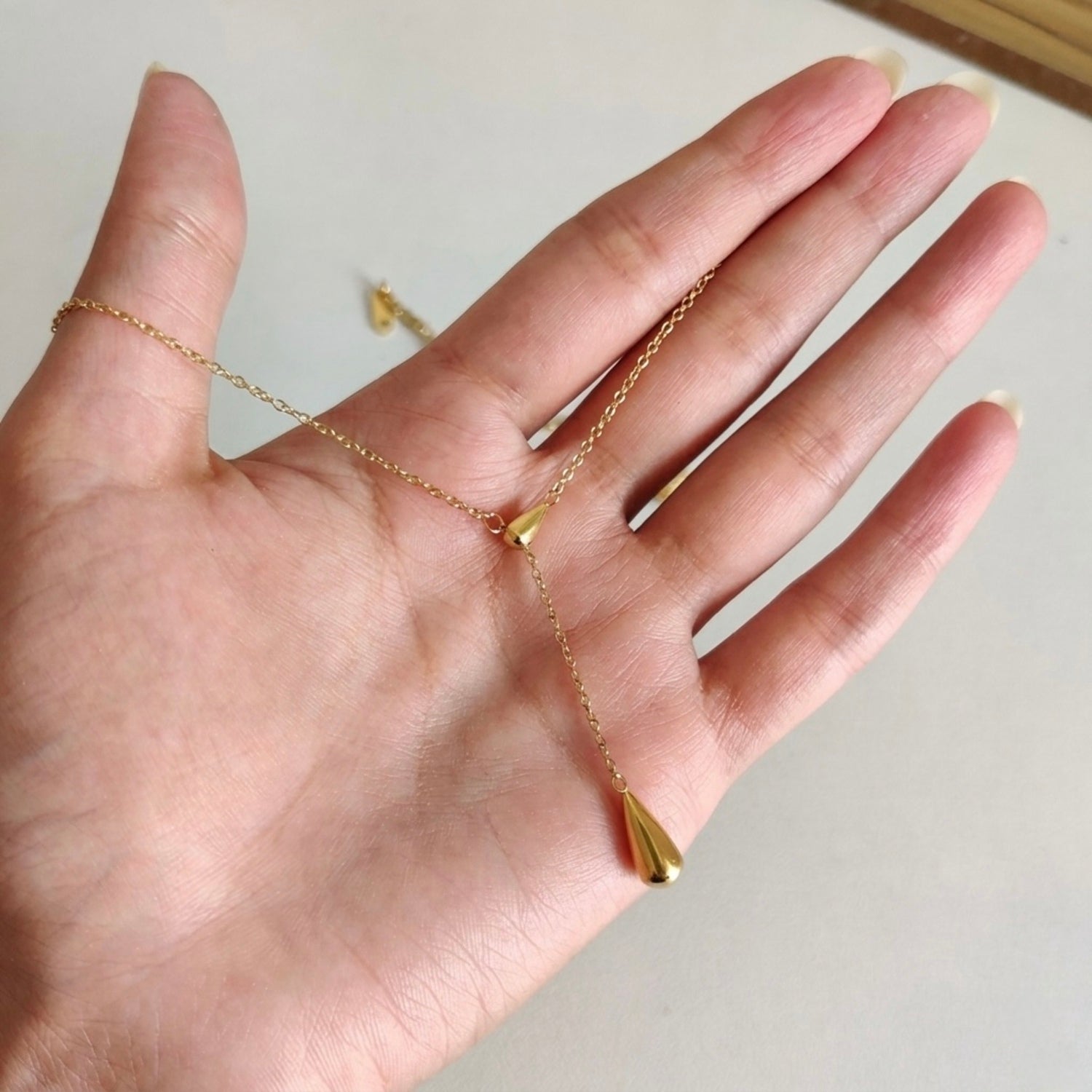 A gold-plated stainless steel chain for women featuring a Y-shaped lariat design with two polished teardrop-shaped pendants