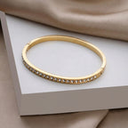 A close-view of a gold-plated eternity bracelet for women featuring a continuous row of round-cut crystals and a secure side-clasp.