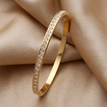 A gold-plated eternity bracelet for women featuring a continuous row of round-cut crystals and a secure side-clasp.