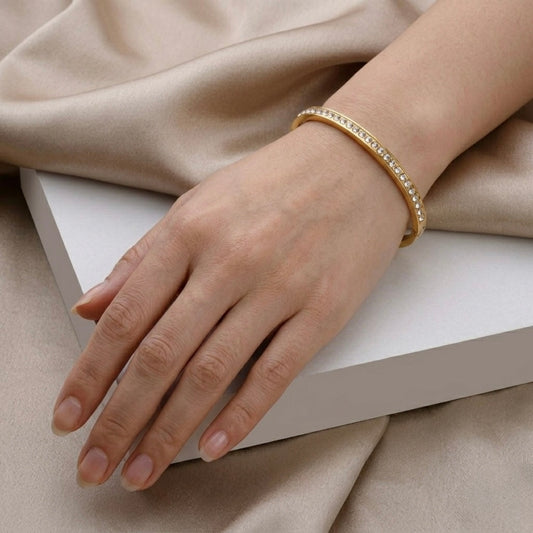 A gold-plated eternity bracelet for women featuring a continuous row of round-cut crystals and a secure side-clasp, shown on a model
