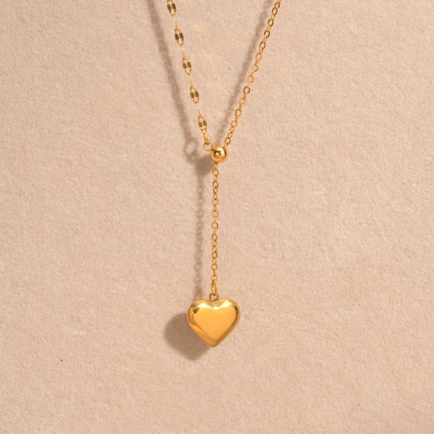 A close-view of a gold-plated stainless steel chain for women featuring a Y-shaped lariat design with a polished 3D puffed heart pendant
