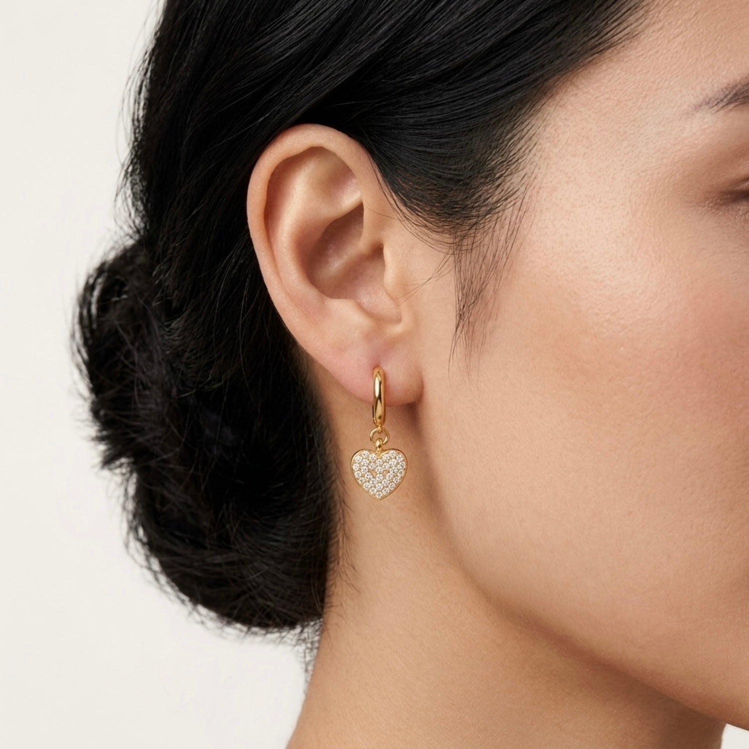 A gold-plated drop earrings for women featuring a heart shape, shown on a model