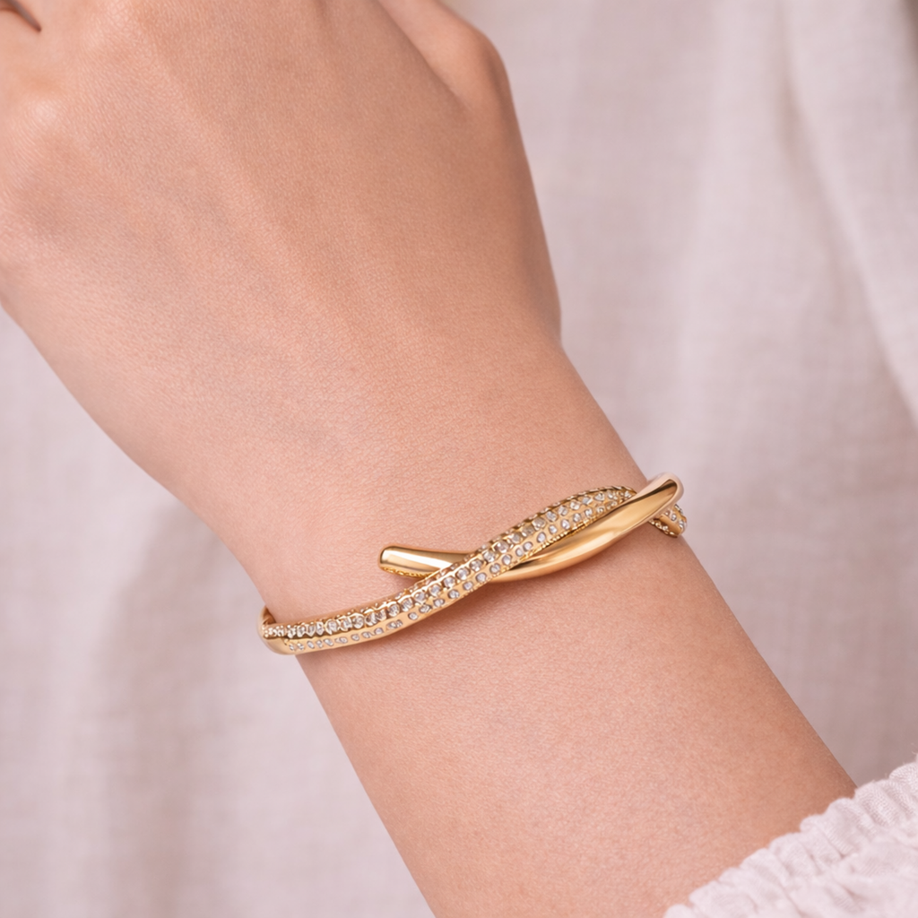A premium gold-plated twisted hinge bangle for women featuring a continuous row of sparkling white stones on a model hand