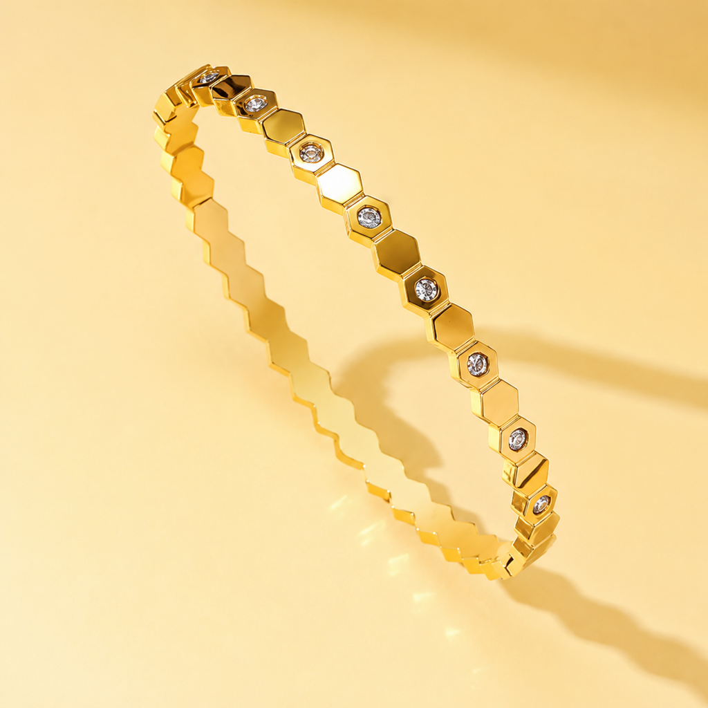 Gold bracelet with hexagonal links and embedded stones on a yellow background