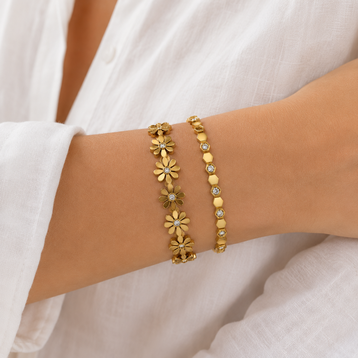 A premium two-piece gold-plated structural bracelet stack for women featuring a geometric crystal honeycomb bangle and a polished gold floral station bangle, on a model