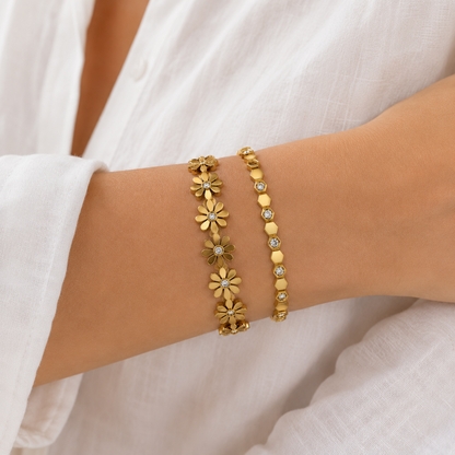 A premium two-piece gold-plated structural bracelet stack for women featuring a geometric crystal honeycomb bangle and a polished gold floral station bangle, on a model