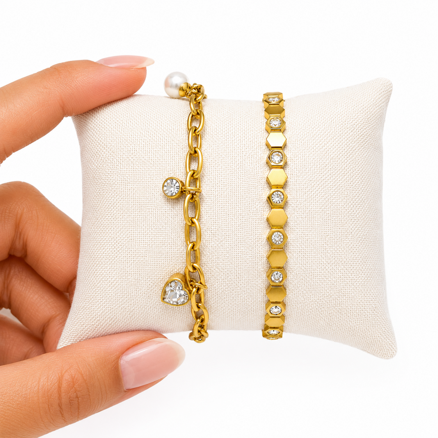 A close-view of a premium two-piece gold-plated bracelet stack for women featuring a chunky paperclip charm chain with a pearl and heart drop next to a geometric honeycomb crystal bangle