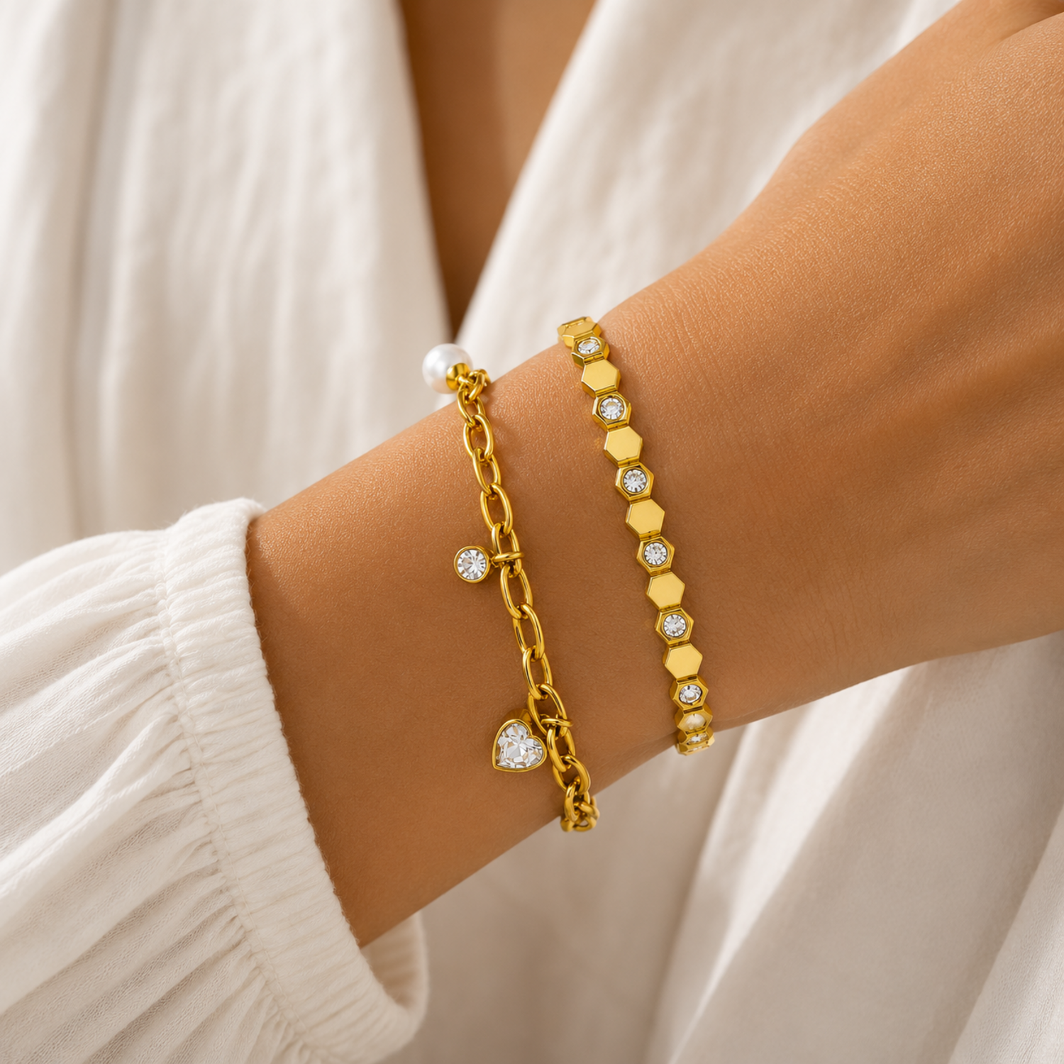 A premium two-piece gold-plated bracelet stack for women featuring a chunky paperclip charm chain with a pearl and heart drop next to a geometric honeycomb crystal bangle, on a model