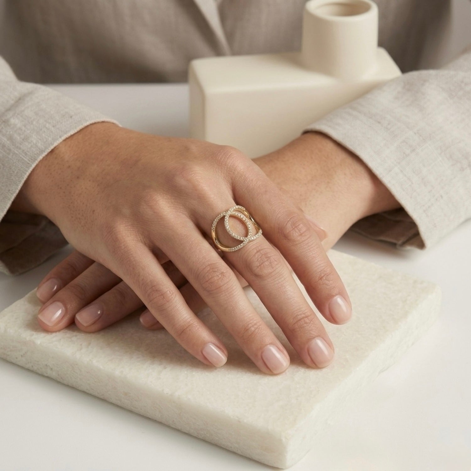 A gold plated adjustable statement ring for women featuring an interlocking oval design with white stones on a model hand