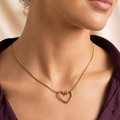 A gold-plated stainless steel chain for women featuring open-heart pendant intertwined with a sleek chain displayed on a model