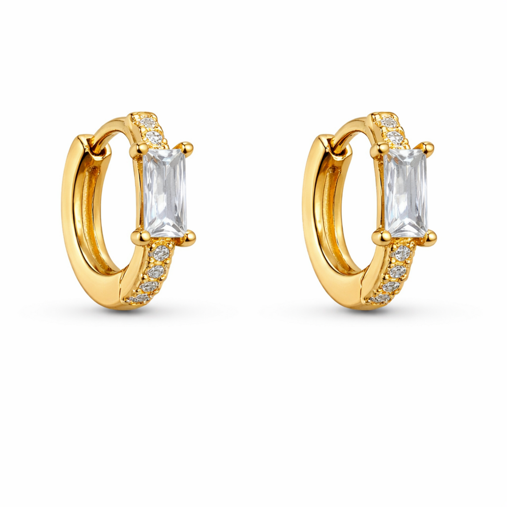 A gold-plated huggie hoop earrings for women featuring a central baguette-cut clear crystal, shown on a clean white background.