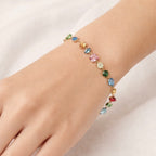 A gold-plated multi-colored stone chain bracelet for women shown on a model hand