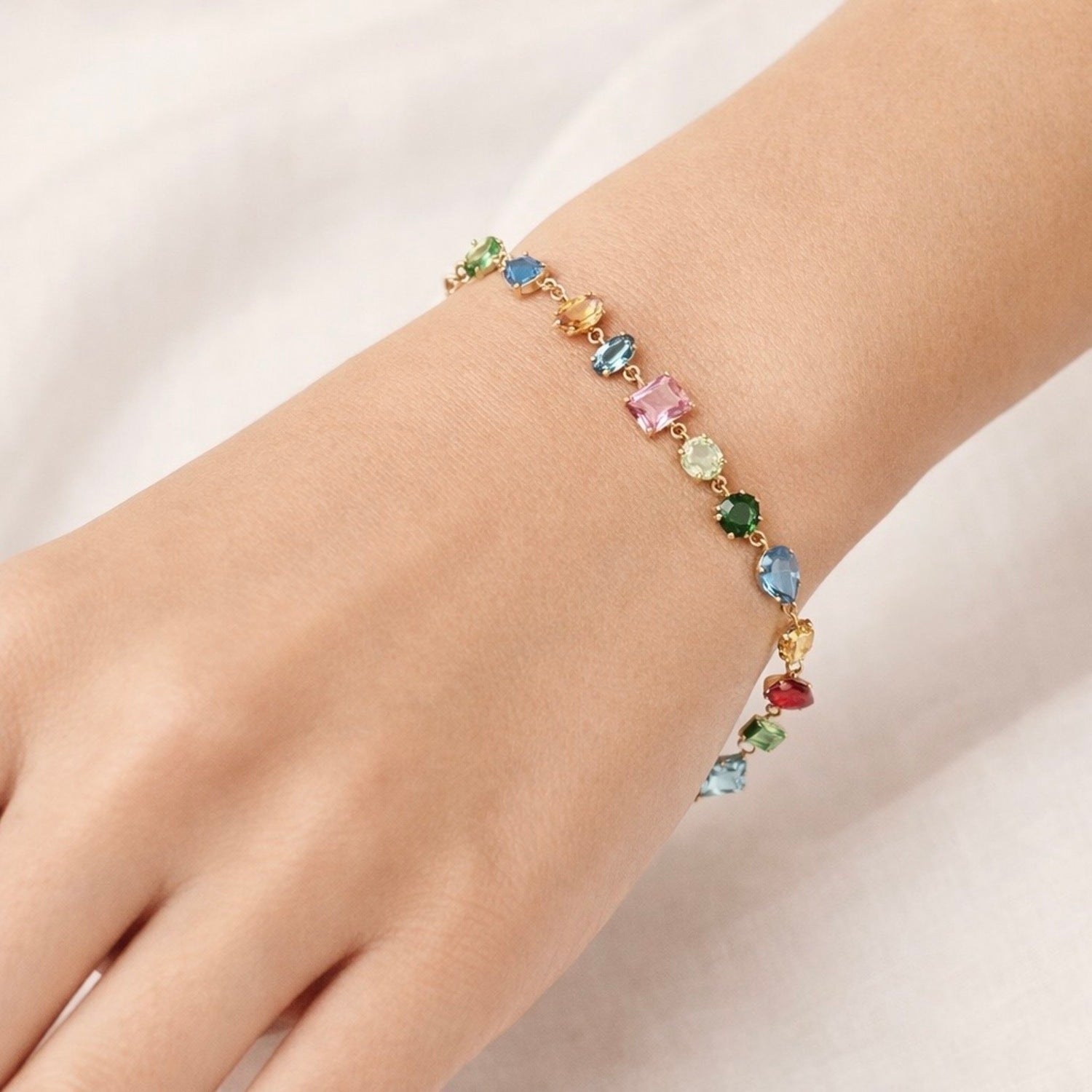 A gold-plated multi-colored stone chain bracelet for women shown on a model hand