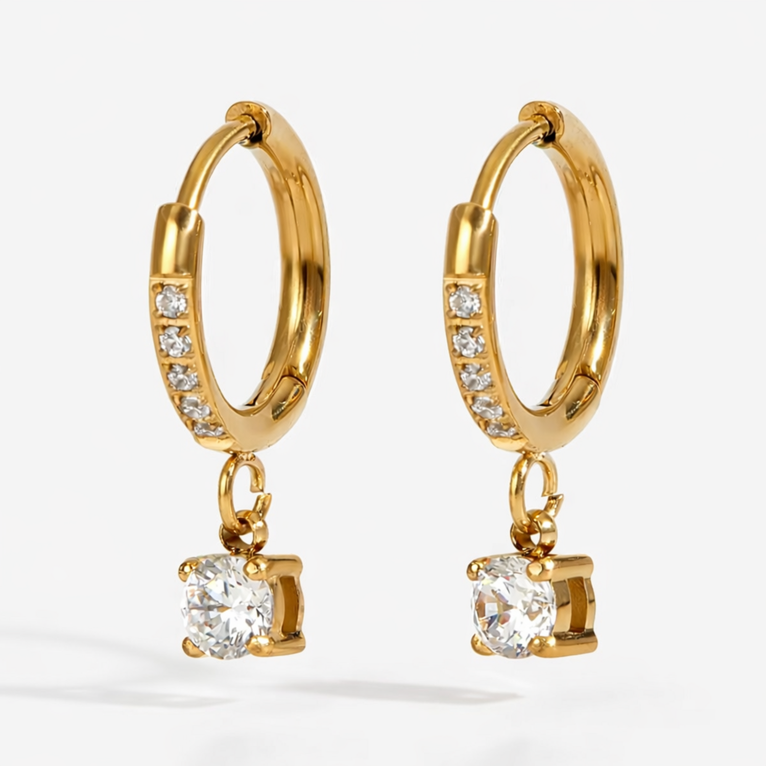 A pair of gold-plated hoop earrings for women featuring a sparkling round-cut crystal drop, shown on a white background.