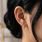 A gold-plated hoop earrings for women featuring a sparkling round-cut crystal drop, shown on a model